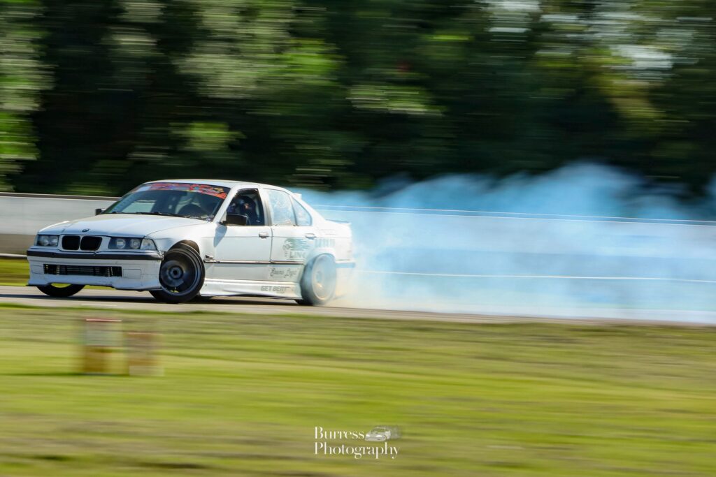 white bmw drifting to victory with tire smoke